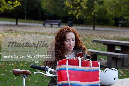 Woman sitting with bicycle in park