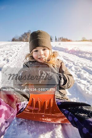 Smiling girl sledding in snow