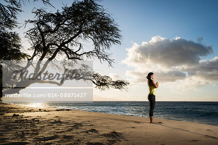 Woman practicing yoga on beach