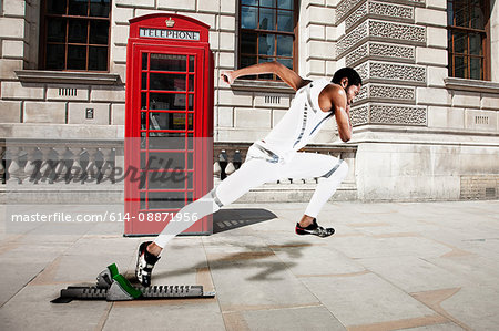 Olympic sprinter on starting line with red telephone box in background