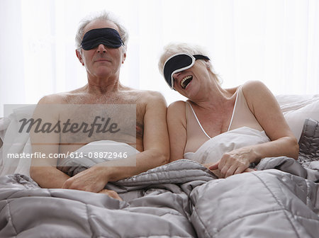 Senior couple wearing face masks in bed