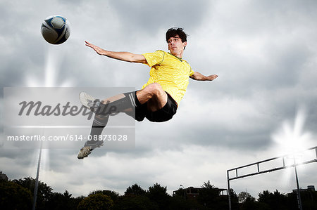 Soccer player leaping to kick ball