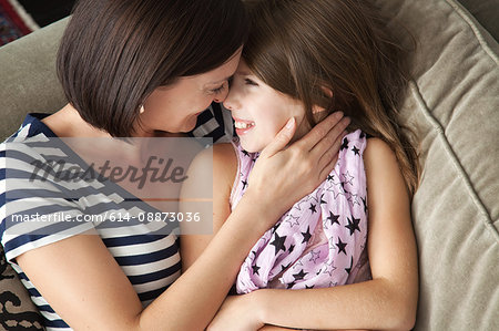 Mid adult woman hugging daughter on sofa