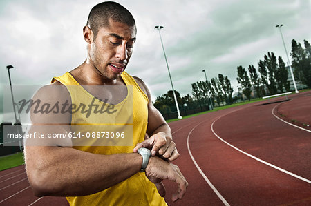 Sprinter looking at watch on race track