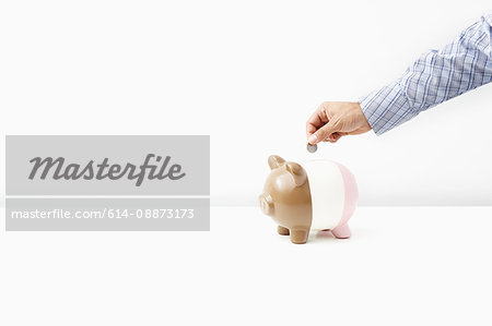 Man putting coin in piggy bank