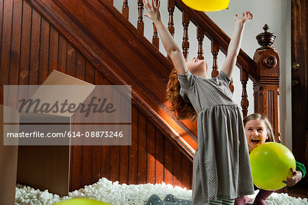 Girl playing with balloon and packing material from cardboard box