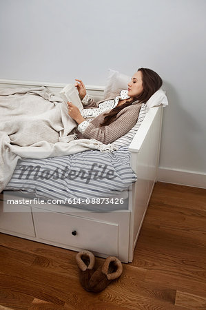 Young woman reading a book in bed