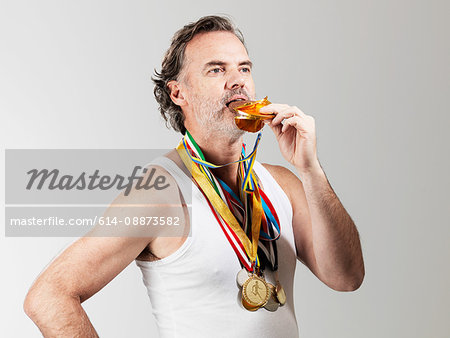 Mature man eating gold coin against white background