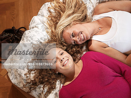 Young woman and mother relaxing together on bed