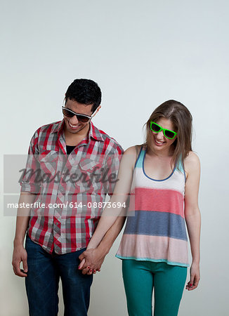 Young couple wearing sunglasses and laughing, studio shot