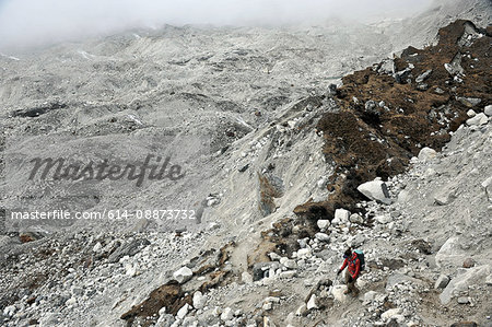 Female trekker descending across the moraine of the Nguzumpa Glacier, Nepal