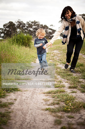 Mother and young son running on dirt track