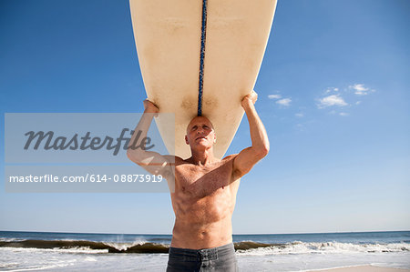 Surfer carrying surfboard on head