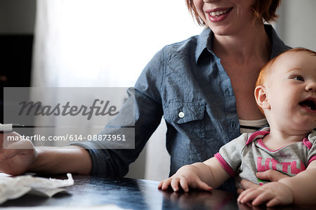 Mother writing with baby daughter on lap