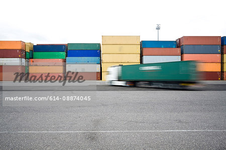 Trucks driving past shipping containers