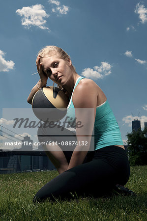 Woman resting with ball, looking at camera