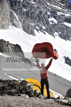Woman shakes her sleeping bag at Camp One on Aconcagua in the Andes Mountains, Mendoza Province, Argentina