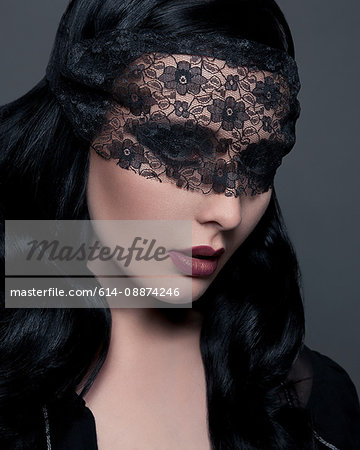 Portrait of young woman with black lace covering eyes