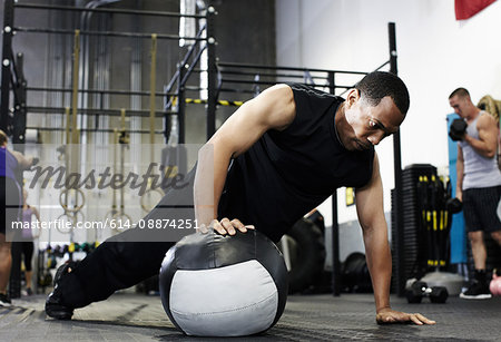 Man doing push up with one hand on medicine ball