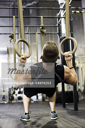 Man using gymnastic rings to do reverse push ups