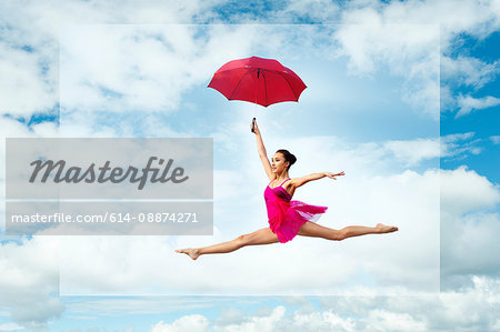 Ballerina with umbrella, leaping against cloudy sky