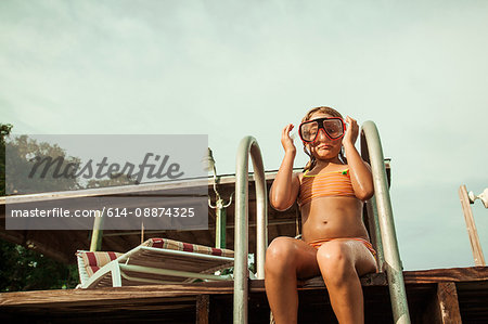 Girl wearing snorkel mask sitting at poolside