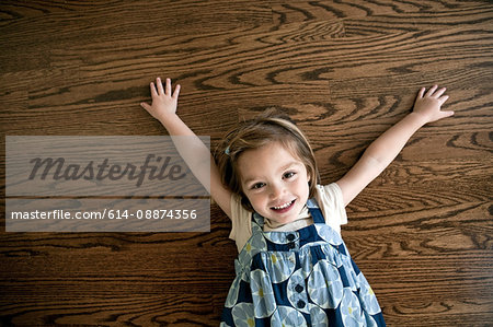 Little girl lying on wooden floor