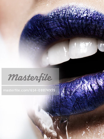 Water pouring over young woman in blue lipstick, close up