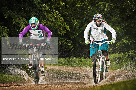 Two female mountain bikers riding through water