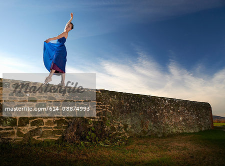 Female dancer poised on stone wall