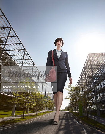 Oversized businesswoman walking on road, low angle view