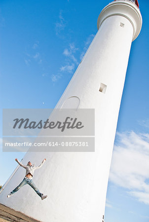 Young man jumping by Split Point Lighthouse, Melbourne, Australia