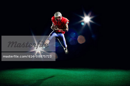 American football player mid air holding ball
