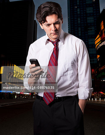 Stressed businessman in city with smartphone