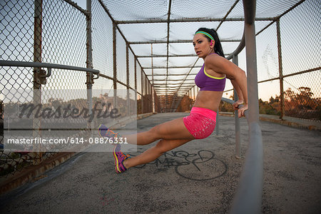 Female jogger stretching on walkway