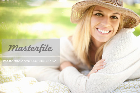 Portrait of young woman lying on picnic blanket in park