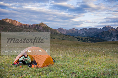 Woman camping, Hasley Basin, West Elk Mountains, Colorado, USA