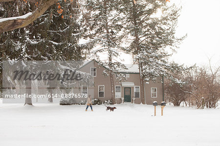 Woman walking dog in snow, Petersburg, Michigan, USA