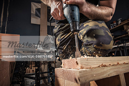 Close up of male carpenter drilling wooden plank in workshop