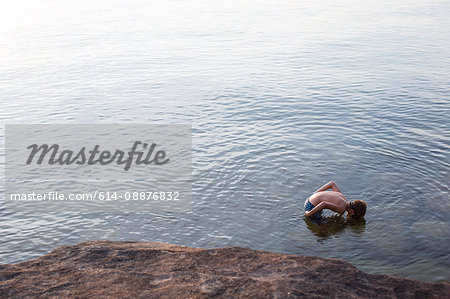 High angle view of teenage boy looking down at Lake Superior, Au Train, Michigan, USA