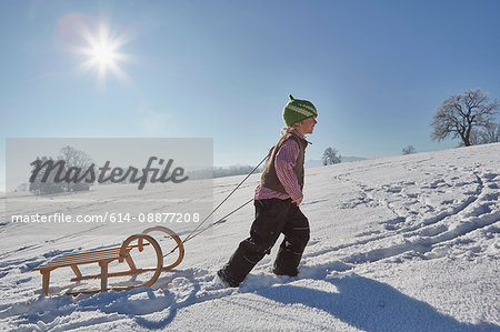 Young boy pulling sled uphill