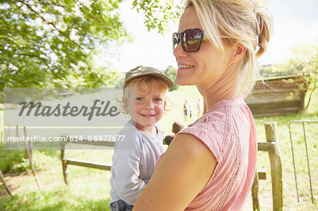 Portrait of mature woman carrying toddler son in field