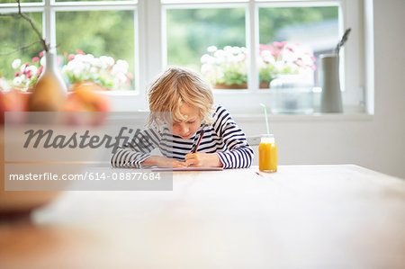 Young boy sitting at table drawing on paper