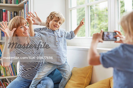 Young boy taking photograph of mother and brother, using smartphone