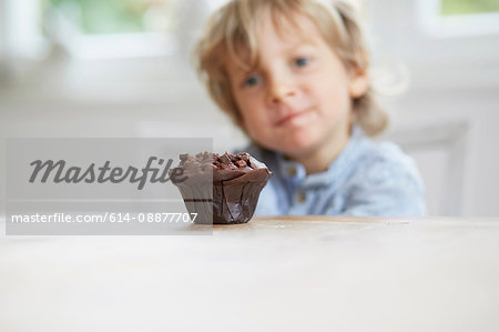 Young boy staring at chocolate muffin