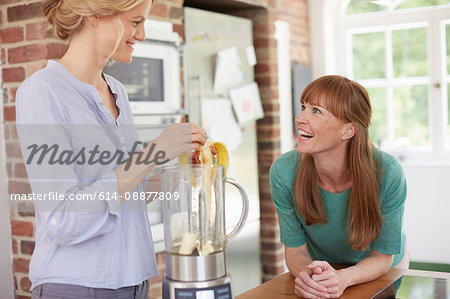 Women using blender and chatting in kitchen