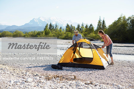 Couple erecting yellow tent near water, Wallgau, Bavaria, Germany