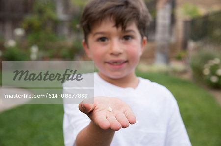 Portrait of young boy holding tooth in hand, focus on hand