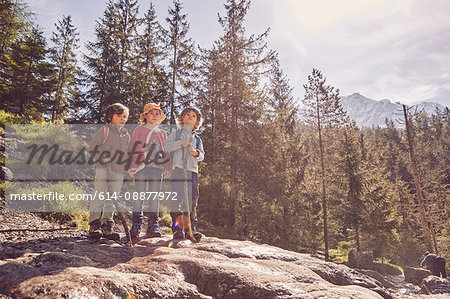 Three children standing on rock in forest