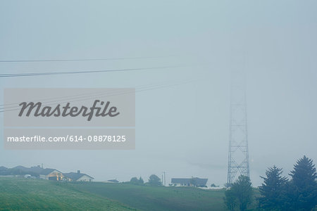 Misty view of electricity cables and  pylon next to houses, Haugesund, Rogaland County, Norway